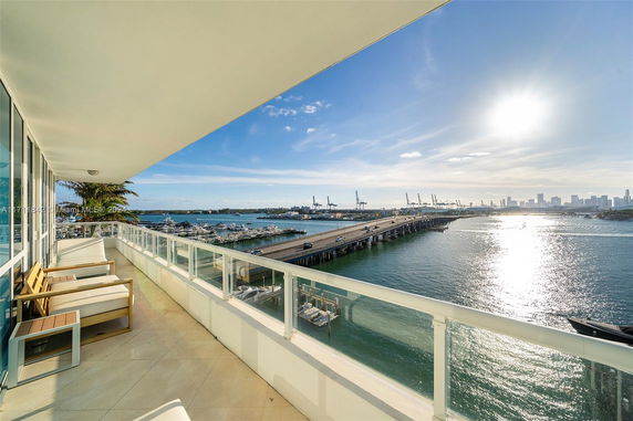 Panoramic view from a balcony overlooking water, a bridge, and city skyline in the distance.