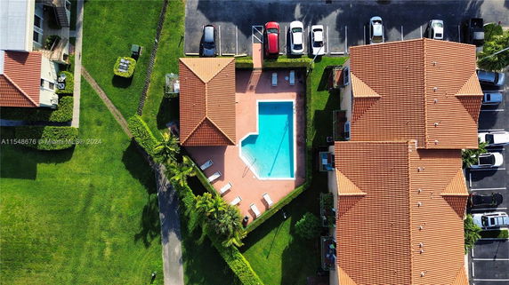 Aerial view of a swimming pool surrounded by residential buildings and parking area.
