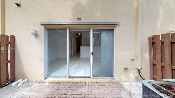 Exterior view of a house with sliding glass doors and a fenced patio area.