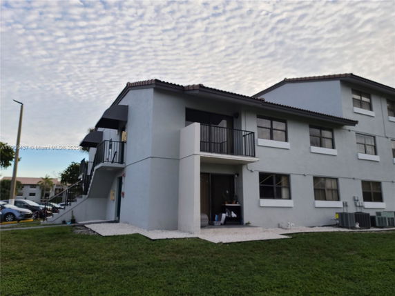 Front view of a multi-story residential building with balconies and a tiled roof.