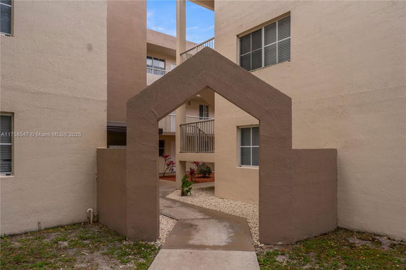 Entrance view of a multi-story building with an archway and visible balconies.