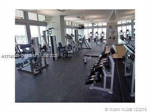Indoor gym area with various exercise equipment and large windows.