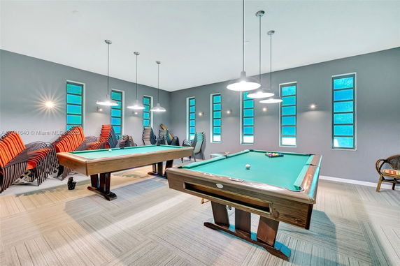 Indoor clubhouse area with two billiard tables and stacked chairs.