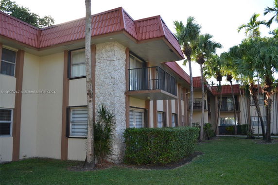 Front view of a two-story apartment building with balconies and a red-tiled roof.