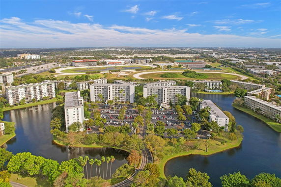 Aerial view of a residential complex with several multi-story buildings surrounded by water bodies and greenery.