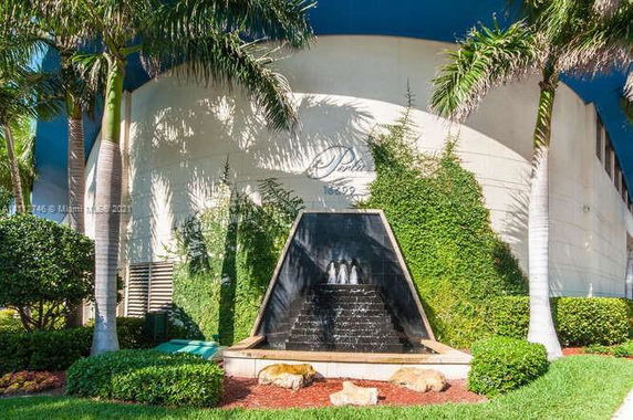 Front view of a building with vine-covered walls and a triangular fountain feature.