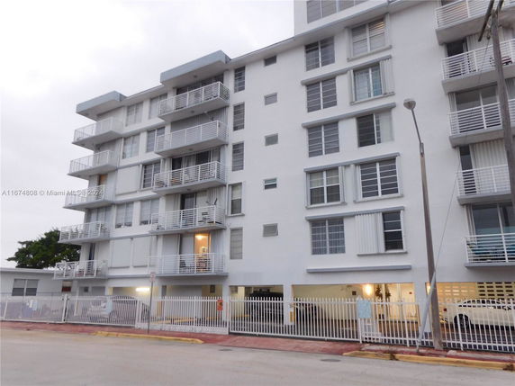 Front view of a multi-story apartment building with balconies and a gated entrance.