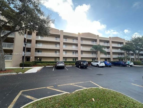 Front view of a multi-story residential building with parking area.