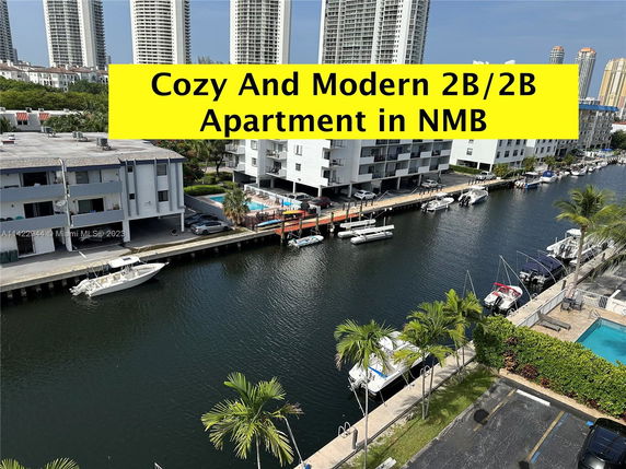 View of apartment buildings along a waterway with boats docked, seen from above.