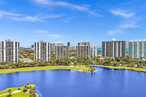 Panoramic view of high-rise buildings with a lake and golf course in the foreground.