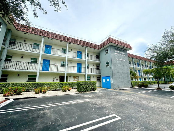 Front view of a multi-story residential building with red-tiled roof and blue doors.