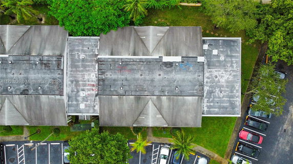 Aerial view of a building with a flat rooftop featuring vents and small structures.
