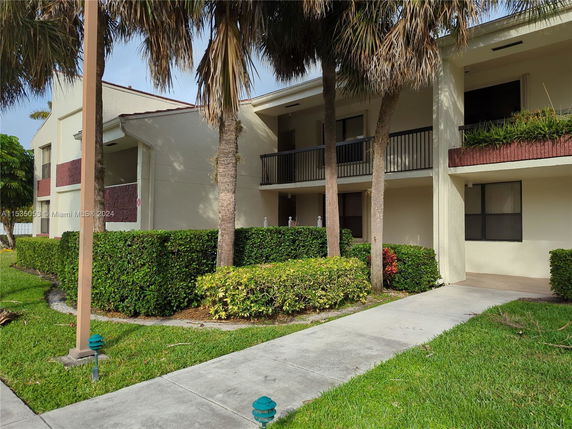 Front view of a two-story residential building with balconies and a pathway.