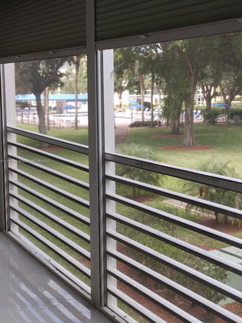 View from a balcony of surrounding areas, including trees and a pool.