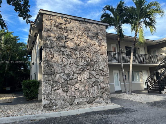 Front view of a two-story building with a stone wall facade and balconies.