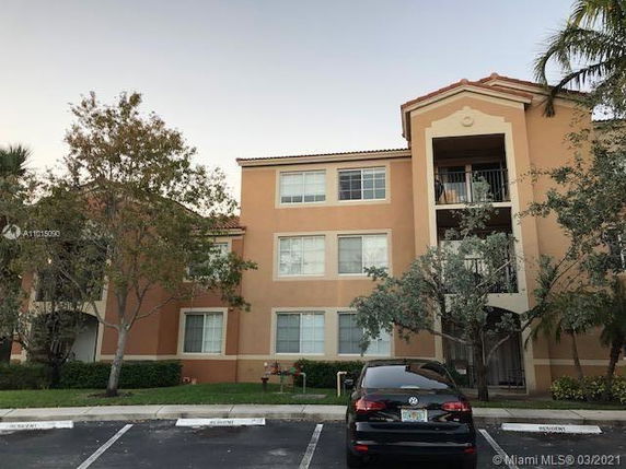Front view of a multi-story apartment building with a parking area.