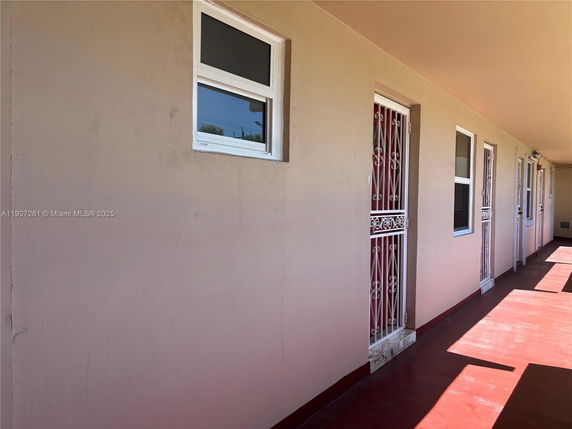 Exterior view of a building corridor with multiple doors and windows.
