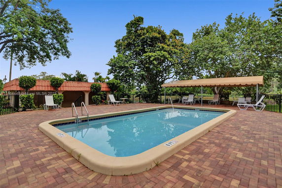 Outdoor swimming pool with surrounding chairs and a canopy area.