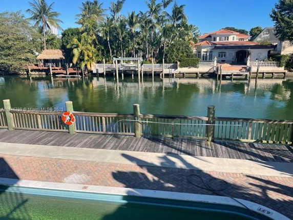Panoramic view of waterfront with a wooden dock and houses across the water.