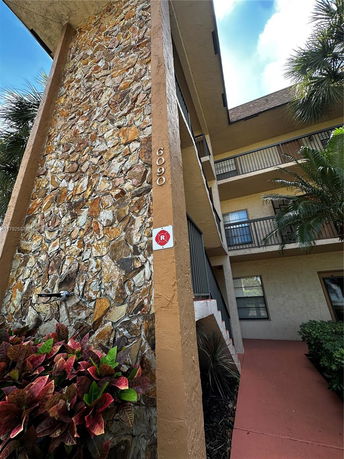 View of a multi-story building with a stone accent wall and numbered address.