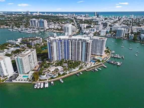 Aerial view of waterfront high-rise buildings with boats docked nearby and a cityscape in the background.