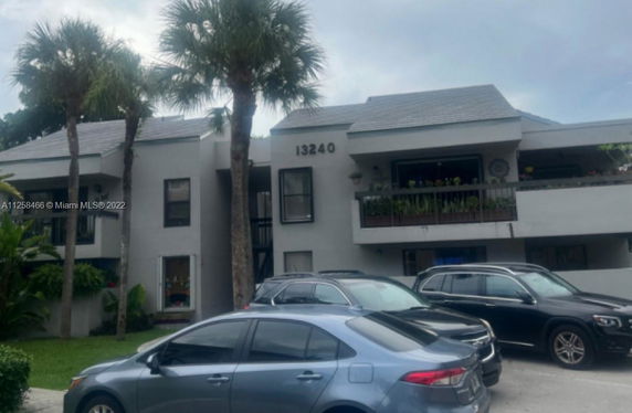 Front view of a multi-story building with balconies and parking area.