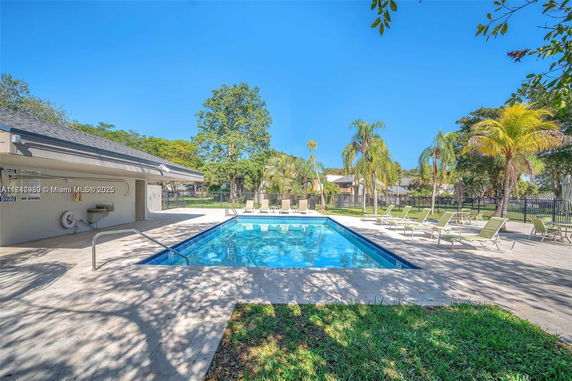 Outdoor swimming pool area with lounge chairs and surrounding greenery.
