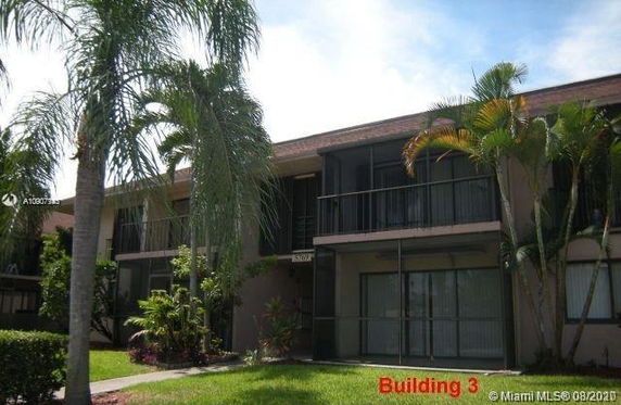 Front view of a two-story building with balconies and palm trees.