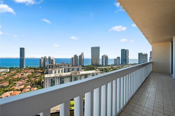 Panoramic view of a city skyline with ocean in the background seen from a balcony.