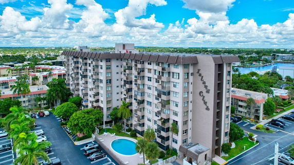 View of a multi-story residential building with balconies and a swimming pool in front.