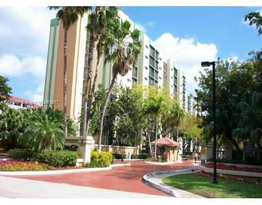 Front view of a multi-story residential building with surrounding trees.