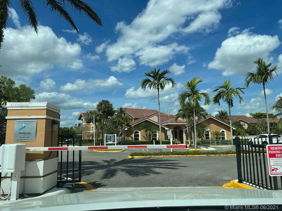 Front view of a building with gated entrance and palm trees.
