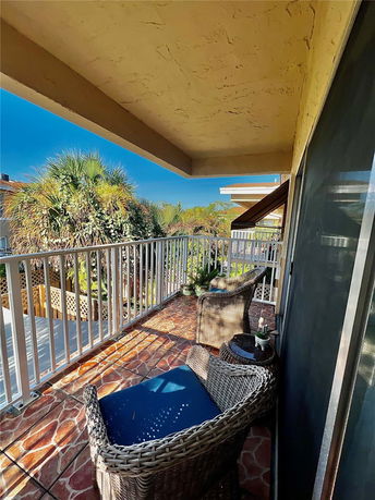 View from a balcony with outdoor furniture, overlooking nearby greenery.