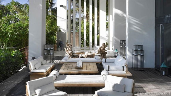 Outdoor seating area with cushioned sofas and chairs, surrounded by greenery.