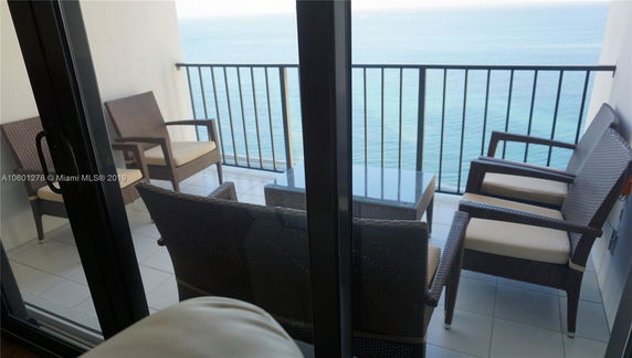 Balcony with wicker furniture overlooking the ocean.