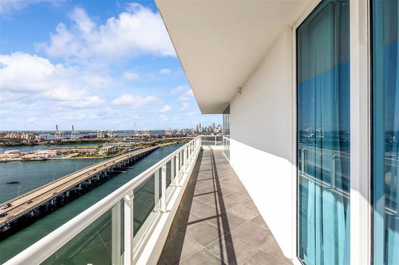 Wide angle view from a balcony overlooking water and a city skyline.