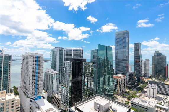 Panoramic view of high-rise buildings with a cityscape and water in the background.