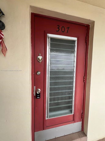 Front door of a building with a red frame and louvered glass window.