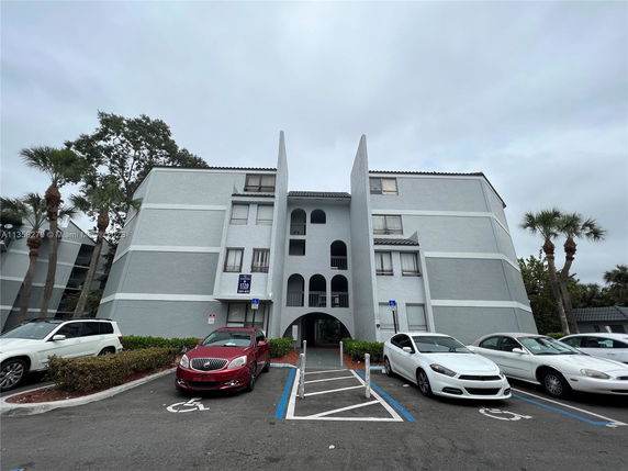 Front view of a multi-story residential building with parking spaces.