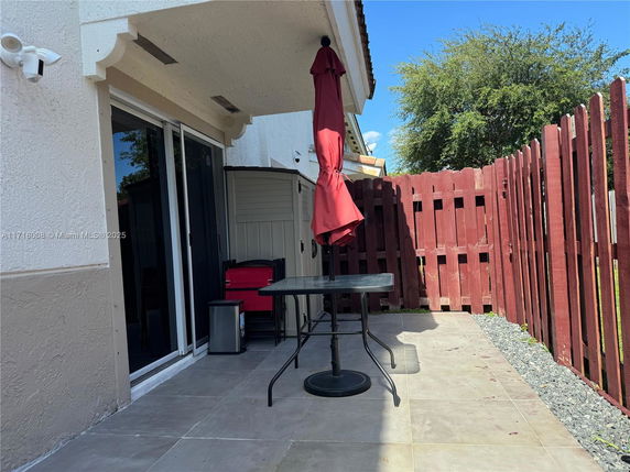 Outdoor patio area beside a house with a red fence and an umbrella.