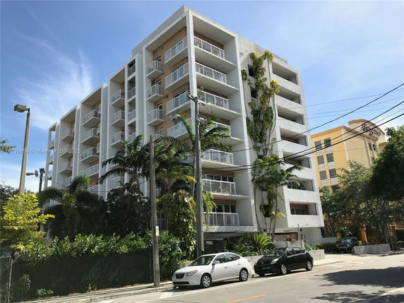 Front view of a multi-story apartment building with balconies and vertical greenery.