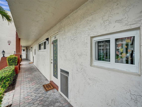 Elevated front entrance of a multi-unit building with decorated doors and windows.