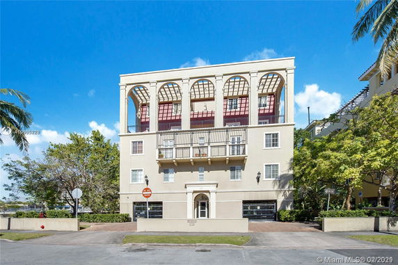 Front view of a multi-story building with arched windows and a balcony.