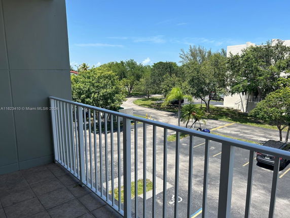 View from a balcony overlooking parking area and trees.
