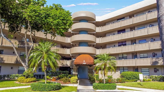 Front view of a multi-story building with round balconies and a central entrance canopy.