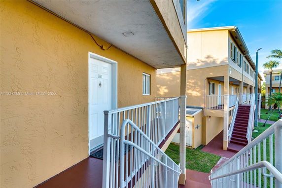 Front view of a multi-story residential building with external staircases and balconies.