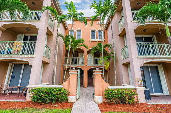 Front view of a multi-story building with balconies and arched entrance.