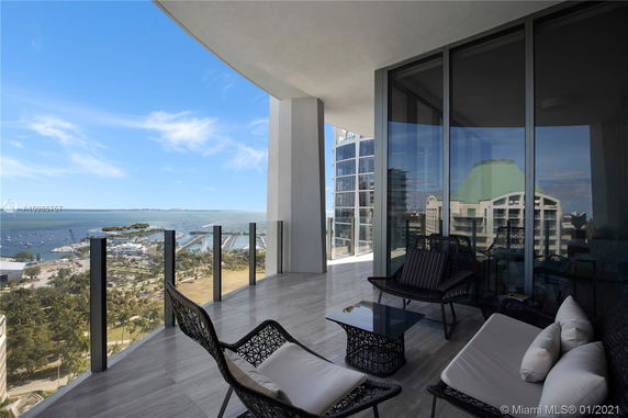 Panoramic view from a balcony overlooking urban and waterfront areas with modern outdoor seating.