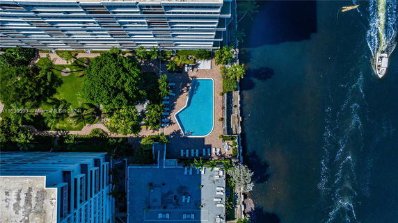 Top view of a building with a swimming pool next to a water body.