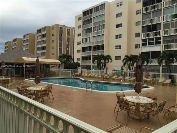 View of a swimming pool area surrounded by multi-story residential buildings.